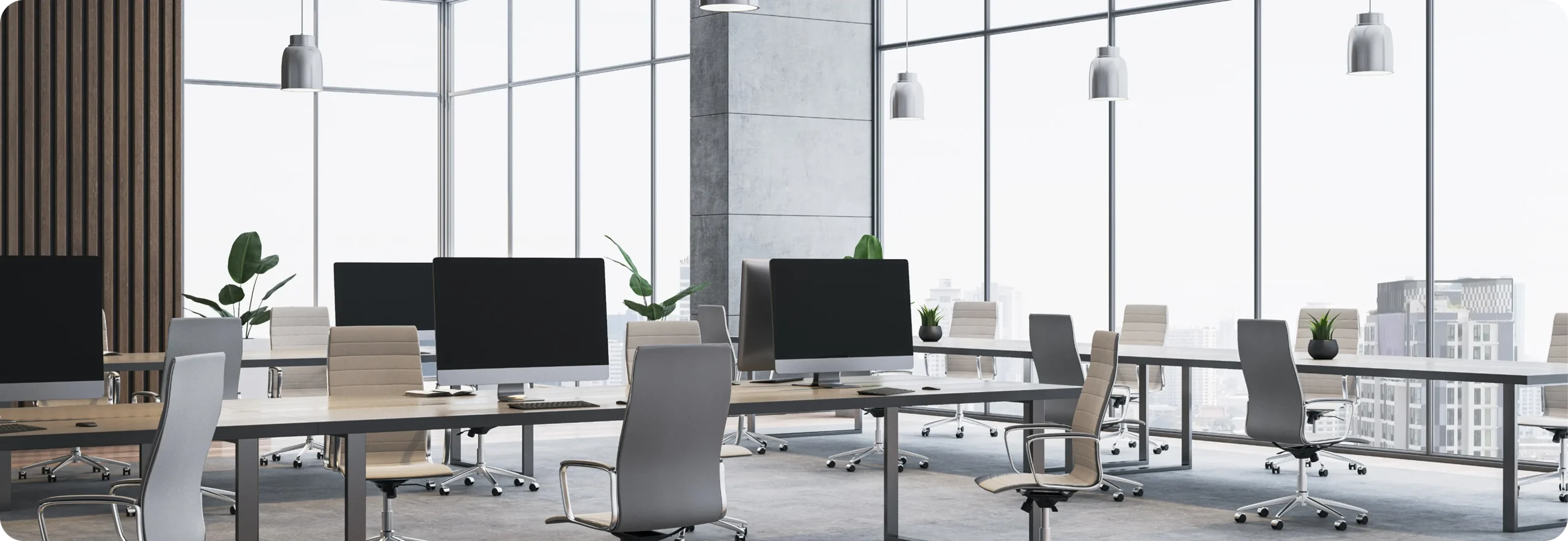 Modern open-plan office with rows of desks, monitors and floor-to-ceiling city views